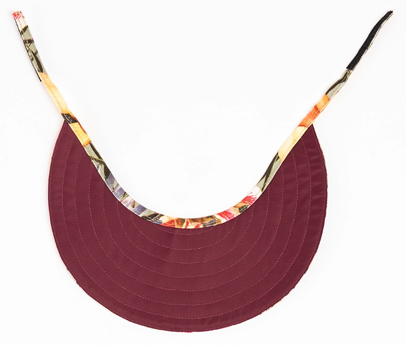 The deep red lining of the reversible sun visor hat has an adjustable velcro fastening.