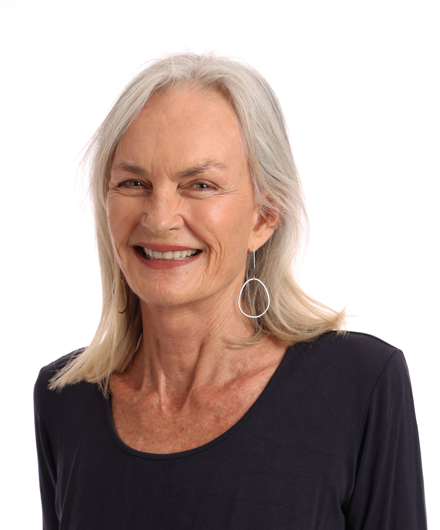 A headshot photo of a lady who is the founder of Wild Things Lifestyle. Her name is Jean Hattingh and she is wearing a black top with hooped silver earrings. She is smiling. The background is completely white.