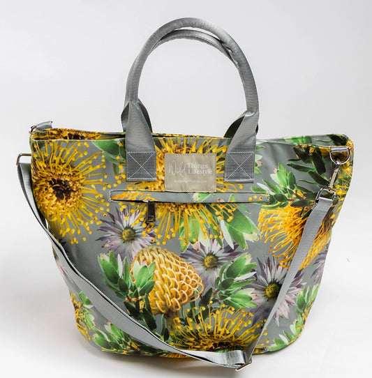 Helena is a large lifestyel tote bag made of water-resistant canvas and depicting yellow pincushion wildflowers on a grey background. 