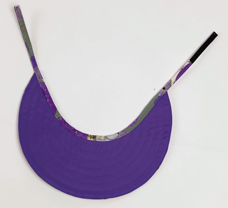 The purple lining side of the wide-brimmed Phoebe sun visor hat, with an adjustable velcro fastening.