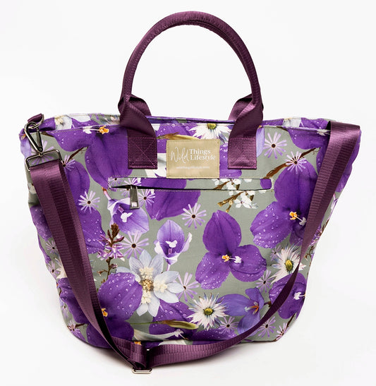 The Phoebe large canvas tote bag from Wild Things Lifestyle depicts purple wild iris flowers on a soft green background. 