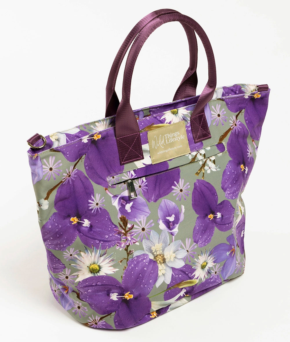 The Phoebe large canvas tote bag with purple wild Iris flowers and purple handles, an external zip pocket and the Wild Things Lifestyle label. 