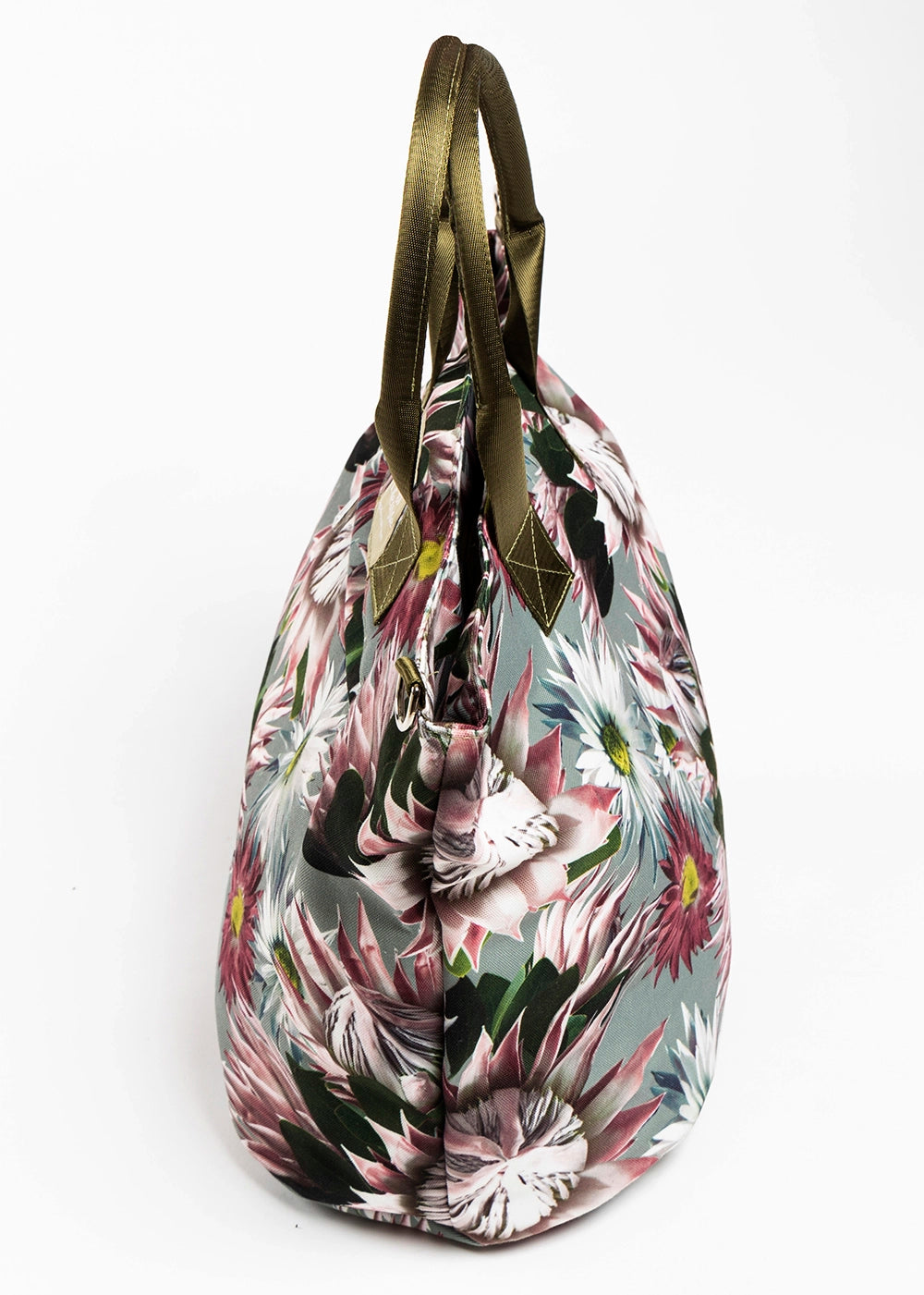 The Protea canvas tote bag which has pink wildflowers on a soft green background with green handles.